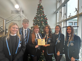St Columba's pupils holding Bronze SCQF Ambassador plaque with Christmas Tree in the background