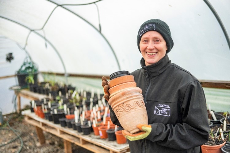 Lee Ryan holding plant pots in a green house