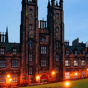 An external photo of Edinburgh University at dusk, with lights illuminating the front of the buildling. Edinburgh University is a credit rating body